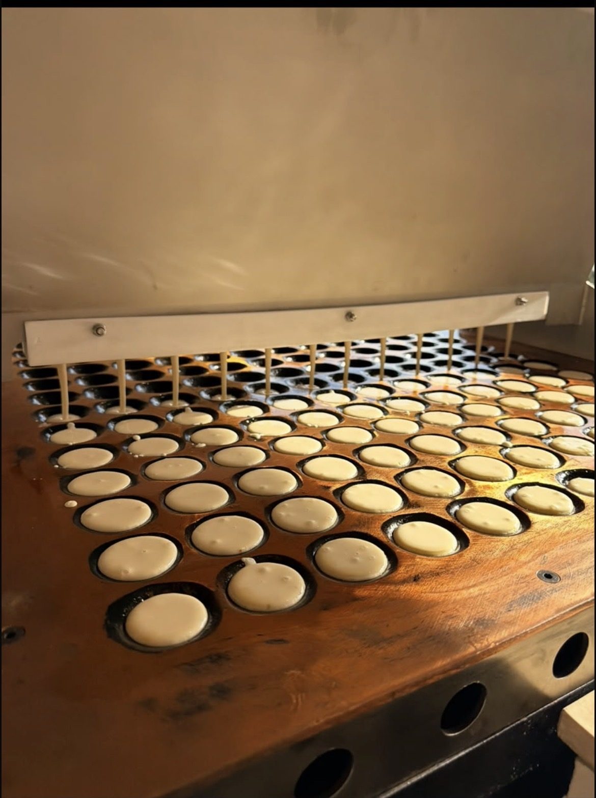 Poffertjes vers gebakken op de koperen plaat van de poffertjeskraam